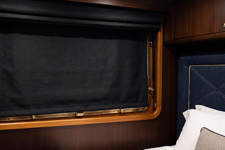 Blackout shades completely lowered over a wooden window in a yacht bedroom