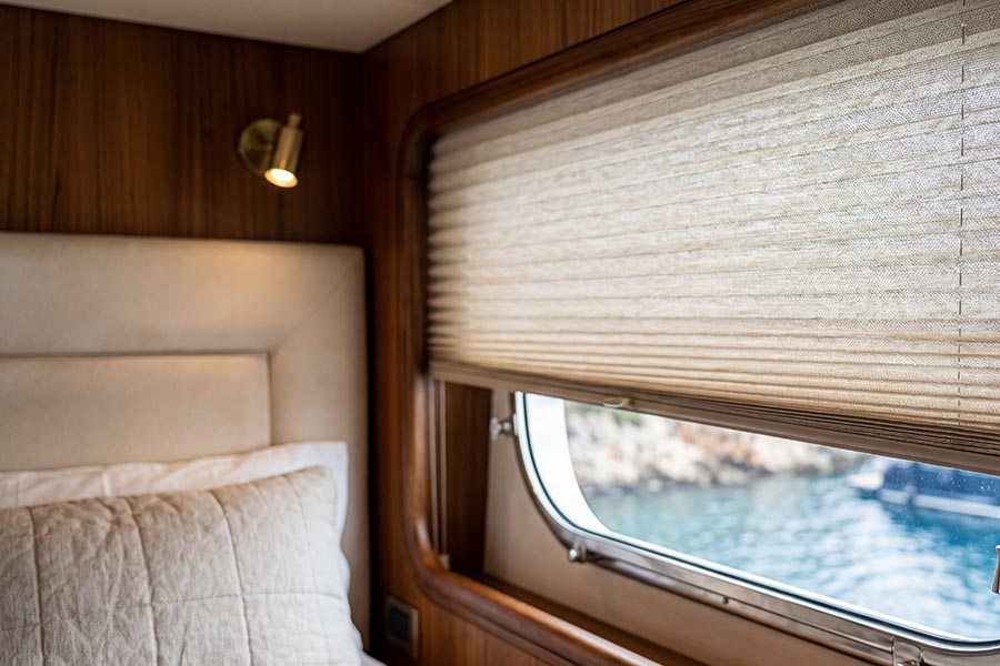 Cellular shades partially raised on a wooden yacht window overlooking the sea