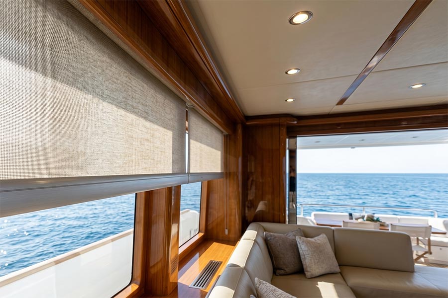 Roller shades lowered over large windows in a luxury yacht cabin living area