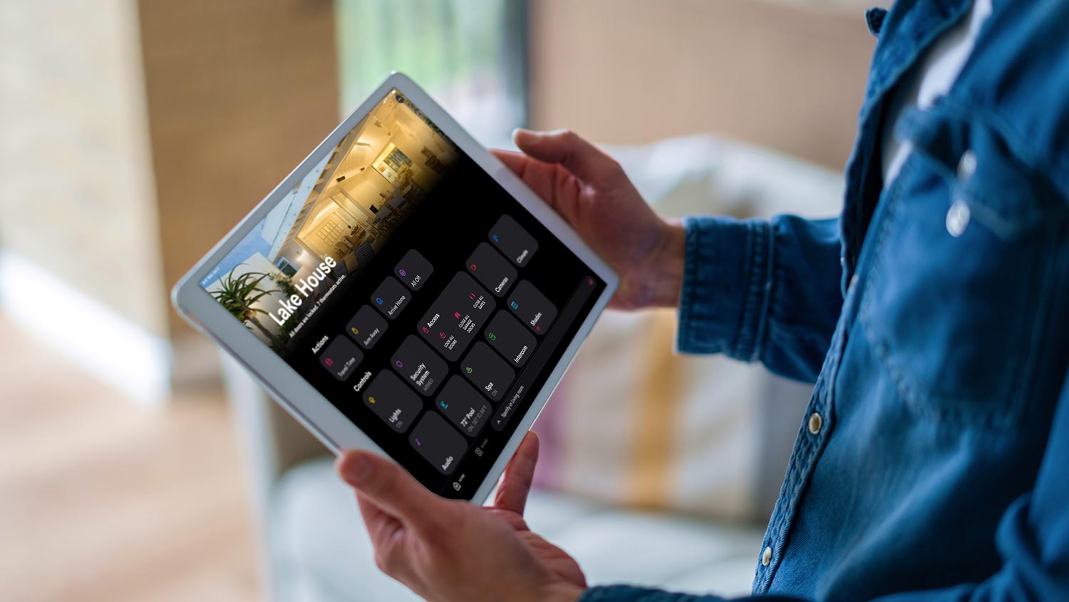 Close-up of a person holding a tablet displaying a smart home automation dashboard interface