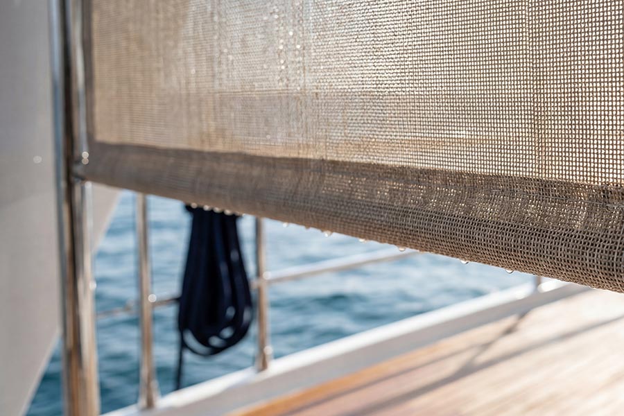 Semi-transparent solar shade rolled down on a boat deck with ocean background